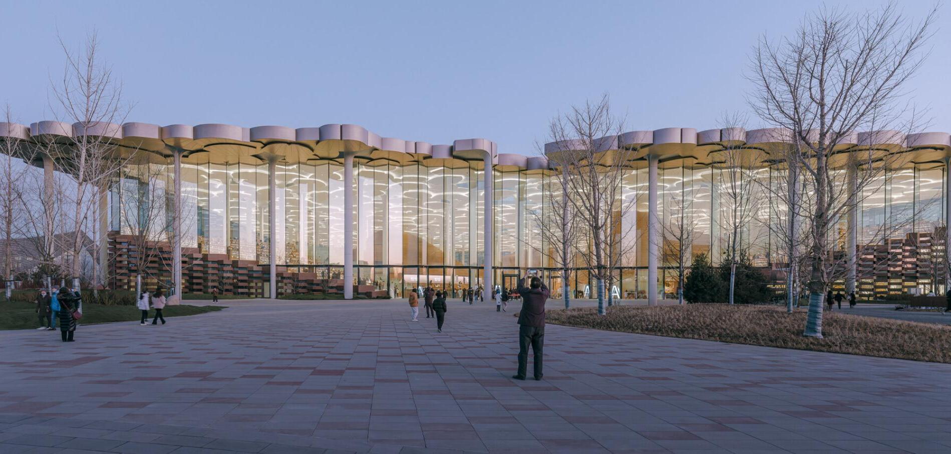 A wide-angle view of the Beijing City Library, showcasing the blend of modern glass curtain walls and LOPO's terracotta panels on the exterior facade, symbolizing the fusion of modernity and tradition.